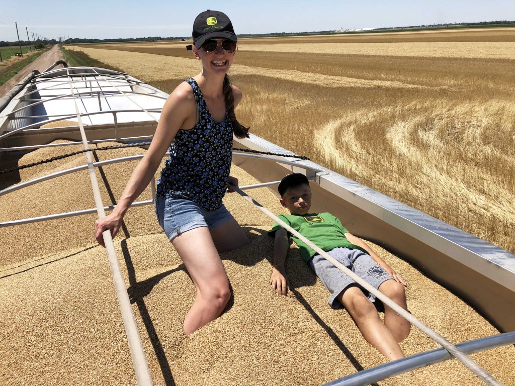 Ann Kent and Stepson Jonah playing in a truck full of wheat on the farm