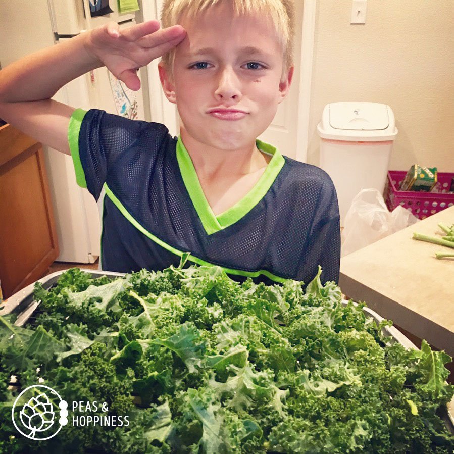8 year old boy saluting a pan of kale chips