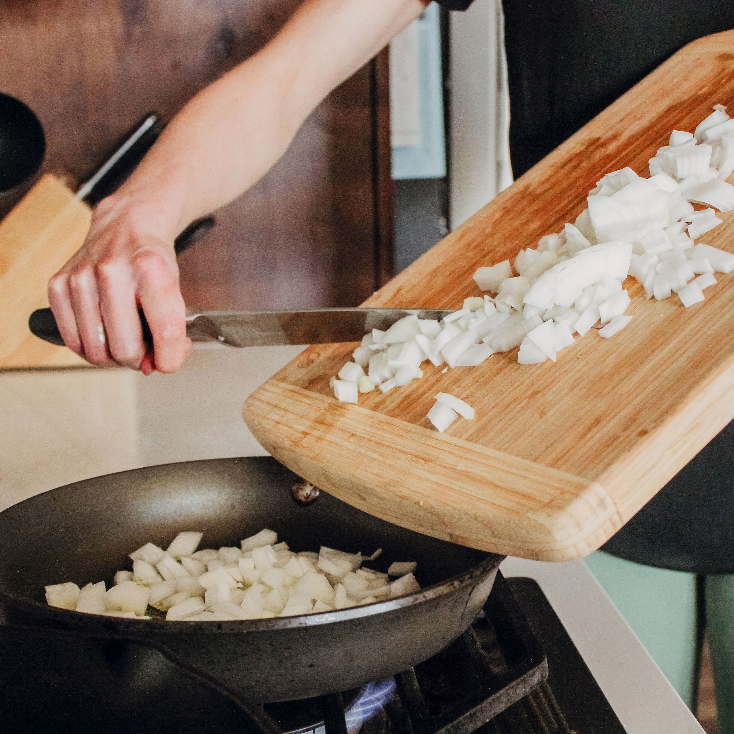 Diced onions on cutting board transfering to skillet