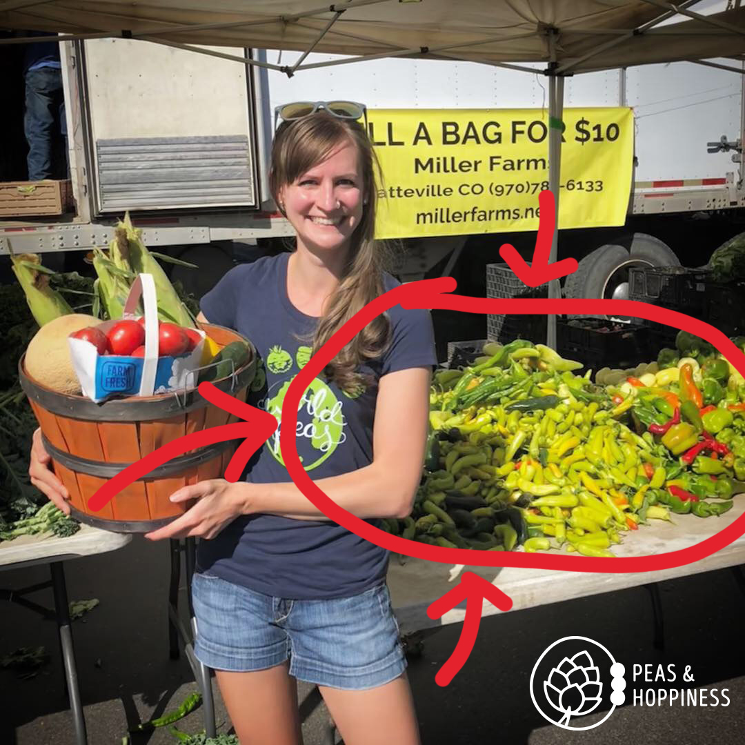 Dietitian Ann standing next to a giant pile of peppers from Miller Farms at the farmers market