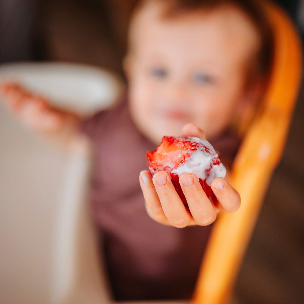 Focus on including whole foods like fruits and vegetables to help fix picky eating - toddler holding a strawberry