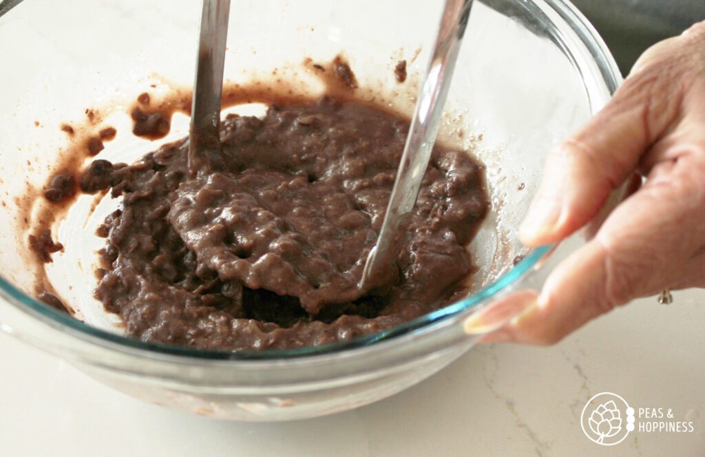 Smashing black beans to make homemade cheddar black bean burgers