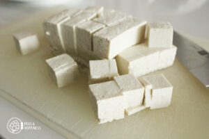 Pile of fresh tofu cubes on a cutting board